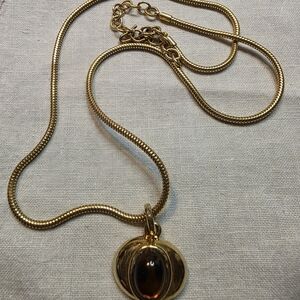 Vintage MonetElegant gold-tone pendant necklace featuring a warm amber cabochon